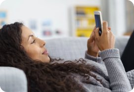 A mother resting on a sofa, looking at her phone.